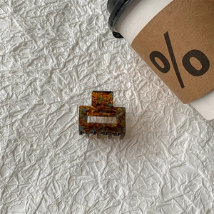 Detailed close-up of a square tortoiseshell hair claw clip with amber and blue textures