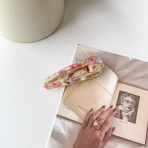 Fermaglio per capelli vintage in acetato e anello dorato testurizzato su libri retrò