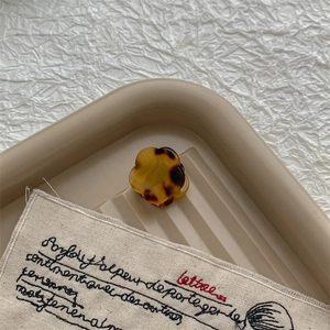 Gros plan d'une mini pince à cheveux fleur en acétate écaille de tortue sur lin