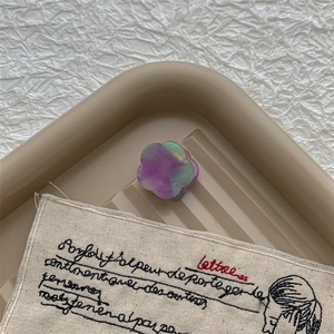 Détail d'une petite pince à cheveux fleurie en acétate avec motif marbré pastel