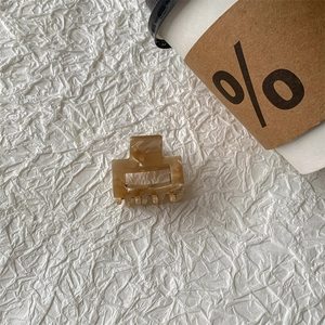 Detail view of a square leopard print acetate hair claw clip on white fabric background
