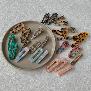 Ensemble de barrettes à cheveux en acétate aux formes variées sur un plat en céramique