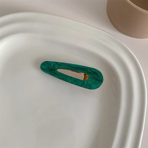 Detailed macro of dark green marble acetate hair clip with gold metal duckbill clamp
