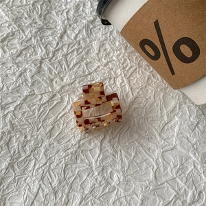 Close-up of brown and beige checkerboard square hair claw clip on minimalist background