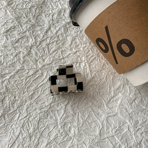 Detail of checkered acetate hair claw clip with black and white geometric pattern