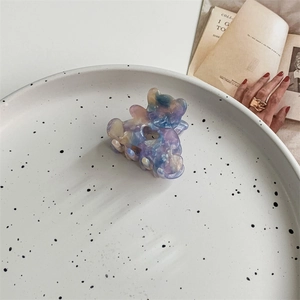 Détail de la pince à cheveux ours avec texture marbrée irisée et découpe en forme de cœur