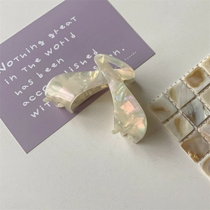 Macro view of a large pearlescent white acetate hair claw clip with elegant twist design