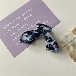 Detailed close-up of a blue marble texture acetate hair claw clip on a minimalist background