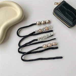Elegant black fabric bun maker set with pearl and floral charms on a grey surface