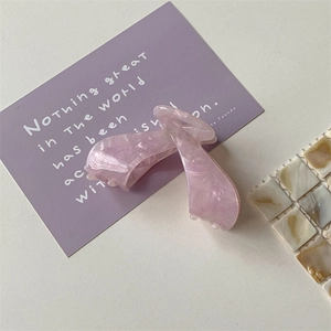 Close-up of pink marble acetate hair claw clip with a glossy finish on decorative card