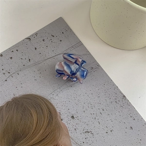 Close-up of small acetate hair claw with blue, pink and white marble texture pattern