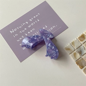 Close-up of a purple marble acetate hair claw clip with a glossy polished finish