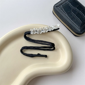 Detailed macro view of black satin hair bun maker with white pearls and small floral charms