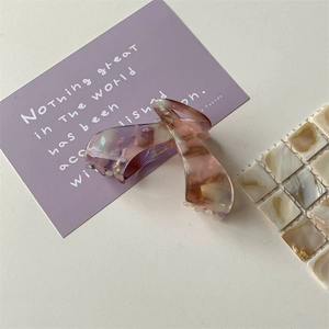 Detail shot of acetate shark hair claw with purple marble ink texture and metal spring