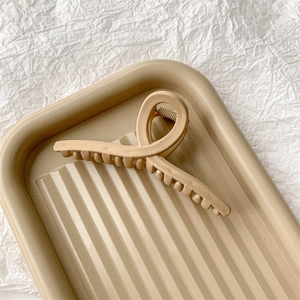 Gros plan sur une pince à cheveux mate beige minimaliste sur un plateau rayé élégant