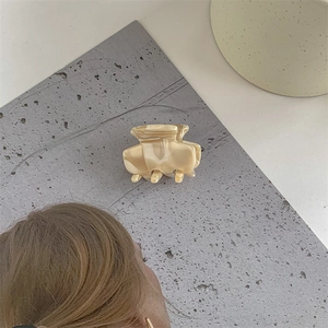 Detail view of a marbled cream acetate hair claw clip with a polished finish and metal spring