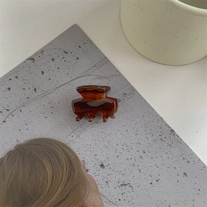 Detail view of a small amber resin hair claw clip with a glossy translucent finish