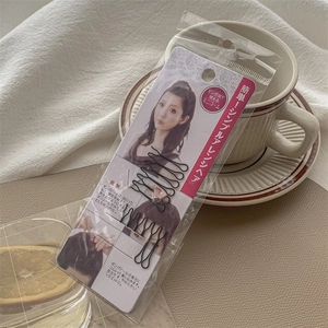 Detail of black metal hair styling clips with wavy U-shape in retail packaging