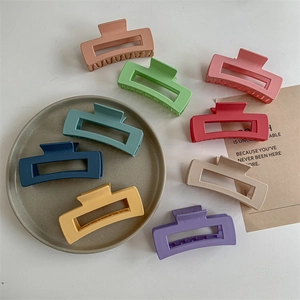 Large matte hollow rectangular hair claw clips in 9 assorted colors on a white tabletop