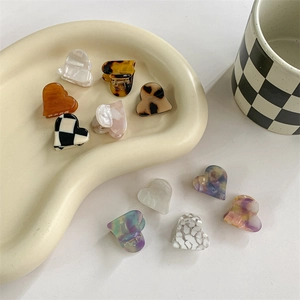 Chic heart-shaped mini acetate hair claws in various patterns on a stylish tray