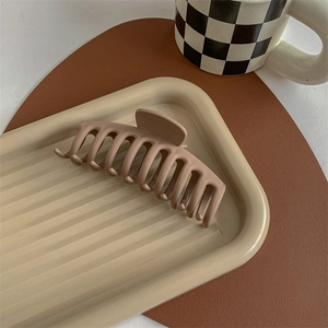 Detail of a large matte light brown claw clip on a stylish textured tray in a cozy setting
