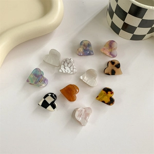 Mini heart-shaped acetate hair claw clips in various patterns like checkerboard and marble