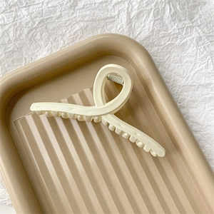 Vue détaillée d'une pince à cheveux mate crème sur un plateau esthétique beige texturé