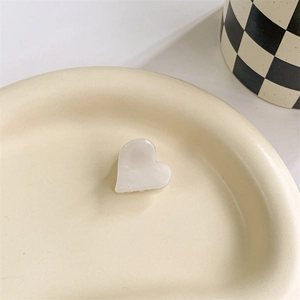 Detail of a creamy heart-shaped hair claw on a ceramic tray with a modern vibe