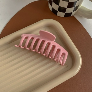 Detailed view of large pink matte hair claw clip on a minimalist tray for elegant styling