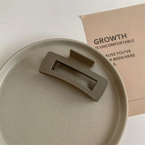 Detailed close-up of a matte coffee large rectangular hair claw clip on a ceramic tray