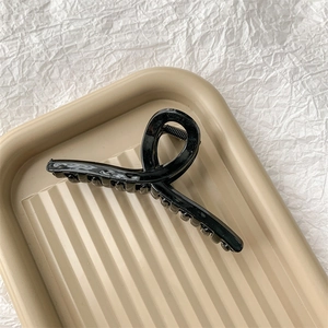 Détail macro d'une grande pince à cheveux noire brillante avec design torsadé et dents de prise