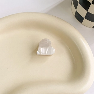 Detail view of heart-shaped acetate hair claw with pearlescent finish on ceramic tray