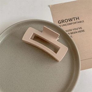 Detail view of large matte beige rectangular hair claw clip on a textured grey plate