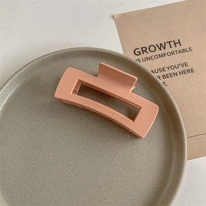 Macro shot of matte peach pink rectangular hair claw clip on a ceramic tray