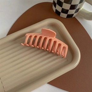 Macro detail of large peach matte hair claw clip on a decorative tray for styling