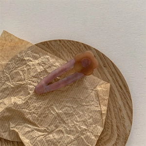 Détail de la pince à cheveux en acétate marbré rose avec fleur mate marron