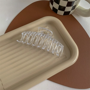 Detail of a large transparent hair claw clip with golden spring on a stylish tray
