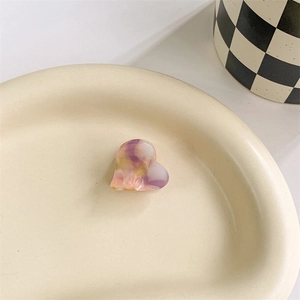Close-up of heart hair clip with pink and yellow marble resin texture in ceramic tray