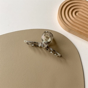 Close-up of marble acetate hair claw with pearlescent finish and pearl embellishments