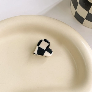 Close-up of heart-shaped acetate hair clip with black and white checkered pattern
