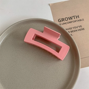 Detail of a large pink matte square hair claw clip on a ceramic tray for thick hair