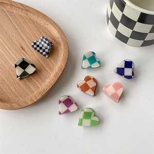 Mini heart-shaped checkerboard hair claws in various colors on a white background