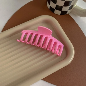 Close-up of pink matte hair claw clip on a decorative tray for elegant hairstyling
