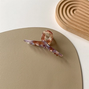 Detail view of large acetate claw clip with pink and blue iridescent marble pattern