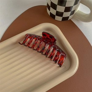 Detail of a large amber red resin shark claw clip on a tray for elegant hair styling