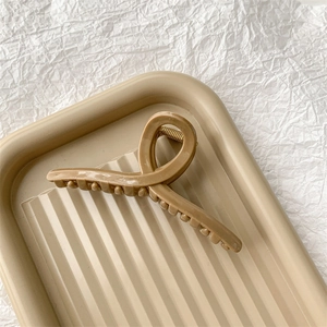 Détail macro d'une pince à cheveux mate beige sur un plateau décoratif chic