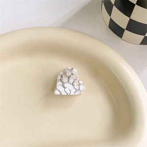 Macro view of a heart-shaped acetate hair clip with marble texture on a tray