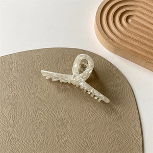 Detail of cream marble acetate hair claw clip with a French minimalist twist design