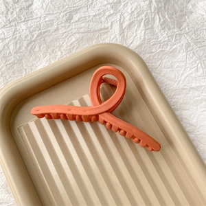 Détail macro d'une grande pince à cheveux orange mat avec une finition texture givrée