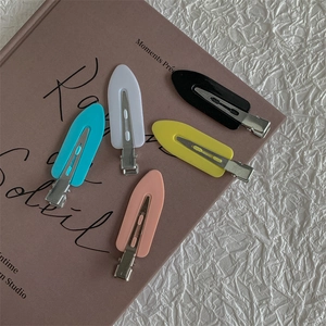Five candy-colored matte duckbill hair clips arranged on a vintage book cover for styling